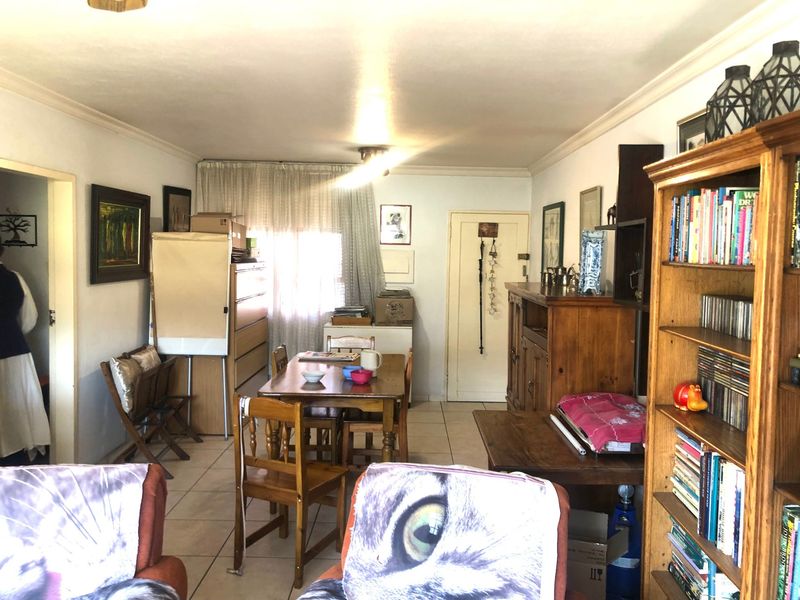 A living and dining area featuring tiled flooring and coved ceiling cornices, offering a functional space with potential for modernization.