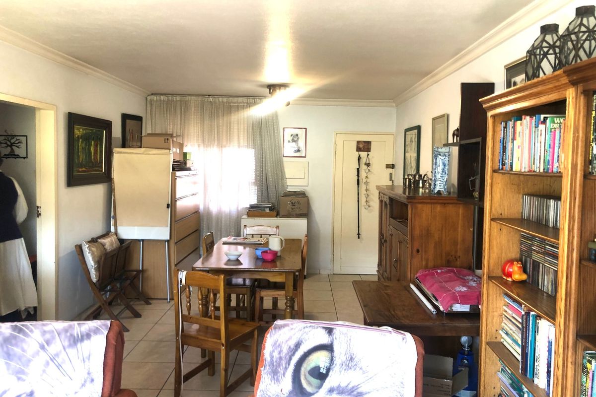 A living and dining area featuring tiled flooring and coved ceiling cornices, offering a functional space with potential for modernization.