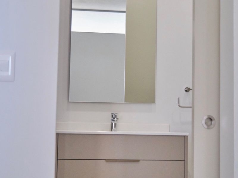 A modern, minimalist bathroom featuring a sleek wall-mounted vanity with an integrated basin, chrome fixtures, and a clean, contemporary aesthetic.