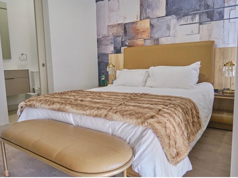 A well-maintained bedroom featuring modern laminate flooring, a stylish feature wall, and direct access to an en-suite bathroom.