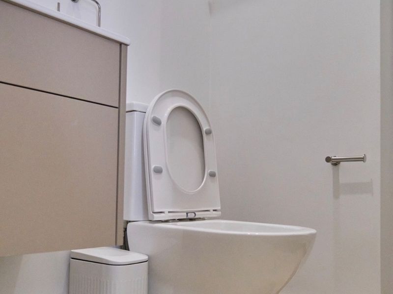 A clean and modern bathroom featuring a wall-mounted vanity, white toilet, and chrome fixtures, finished with neutral floor tiles.