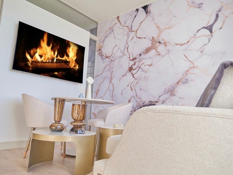 A modern living area featuring light laminate flooring and a decorative marble-effect feature wall, creating a bright and contemporary atmosphere.