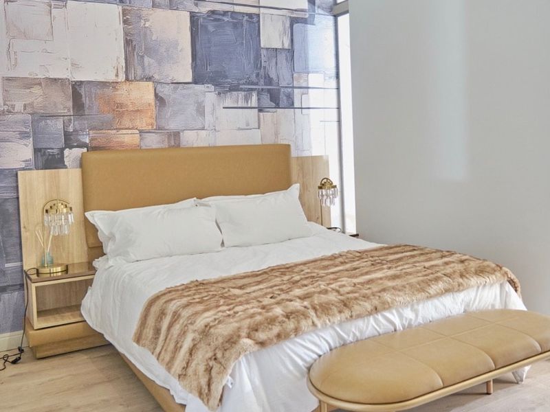 A well-maintained bedroom featuring light laminate flooring, a modern feature wall, and a high-level clerestory window providing natural light.