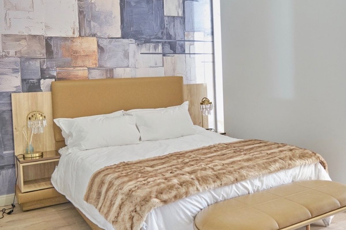 A well-maintained bedroom featuring light laminate flooring, a modern feature wall, and a high-level clerestory window providing natural light.