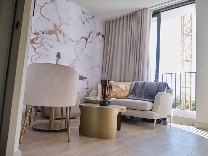 Modern living area featuring laminate flooring, a striking marble-effect feature wall, and large sliding glass doors opening to a private balcony.