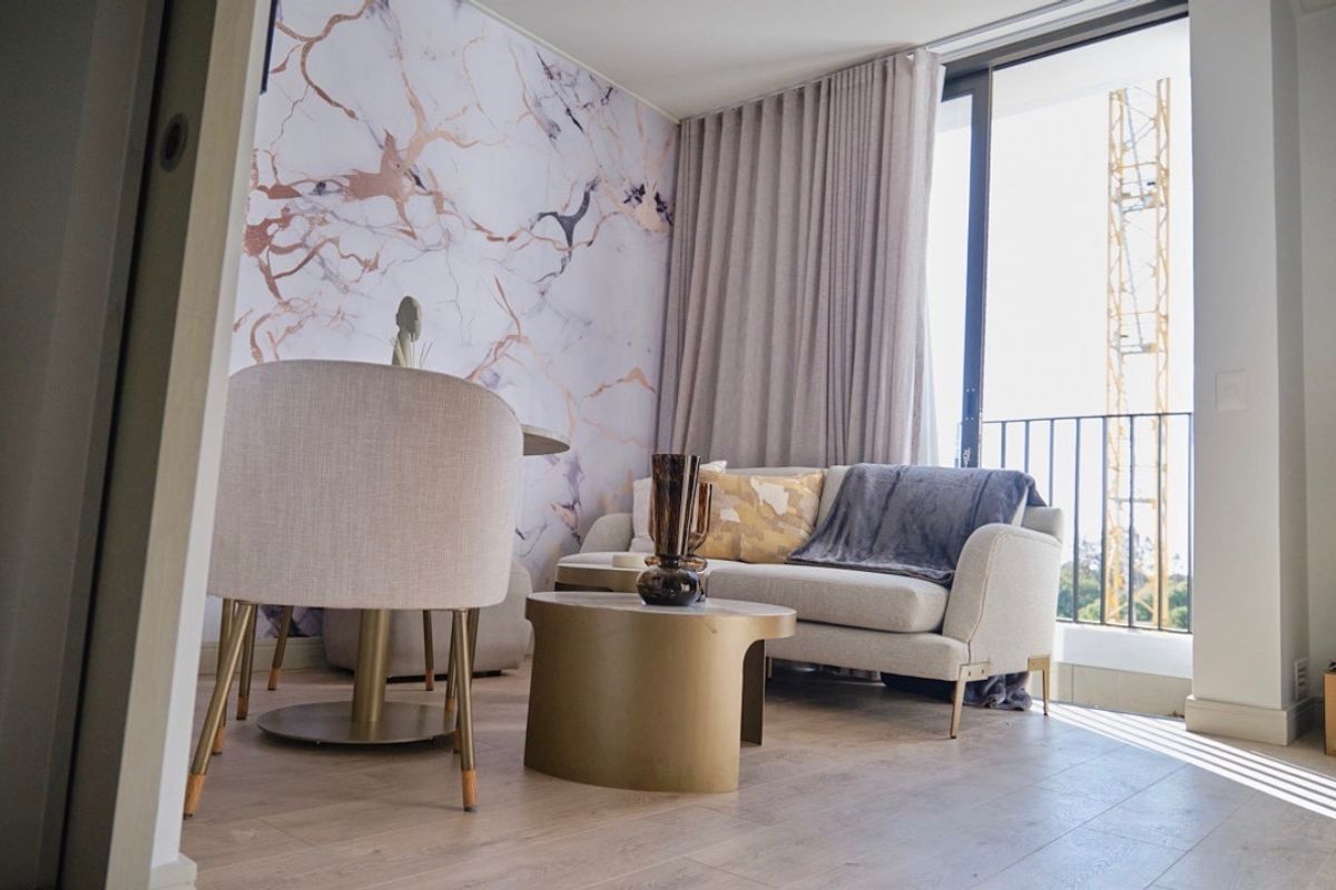Modern living area featuring laminate flooring, a striking marble-effect feature wall, and large sliding glass doors opening to a private balcony.