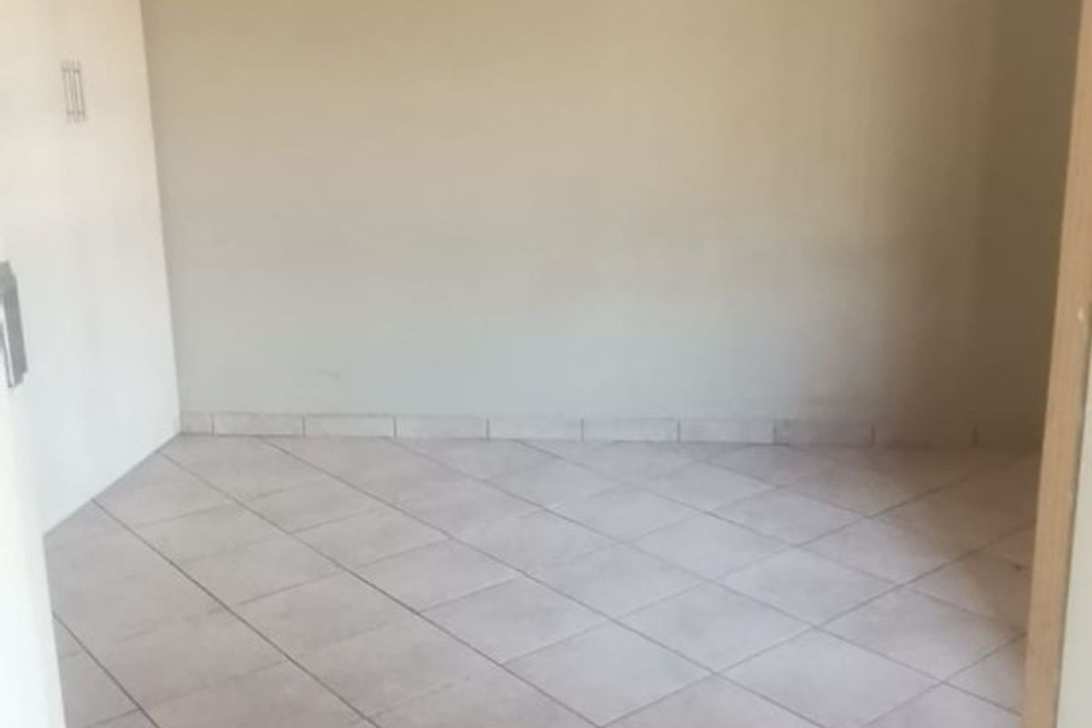 An empty bedroom featuring neutral tiled flooring and a built-in cupboard, offering a blank canvas for personalization.