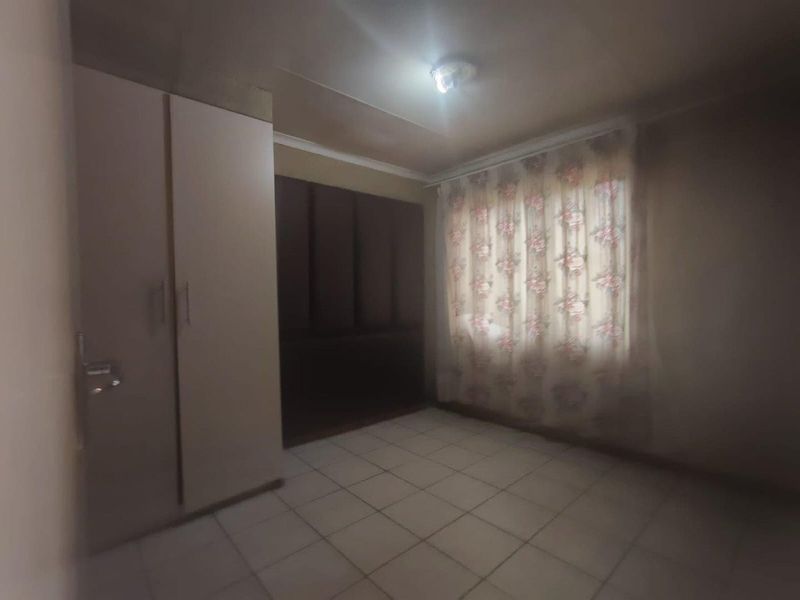 A vacant bedroom featuring tiled flooring and built-in cupboards, requiring cosmetic updates to improve its overall appeal and condition.
