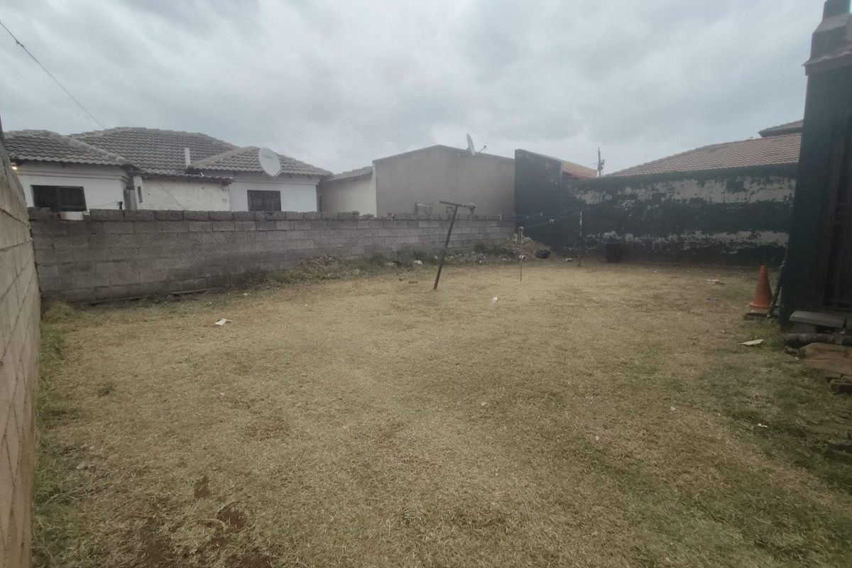 A spacious rear garden area enclosed by perimeter masonry walls, featuring a dry lawn and a fixed clothesline.