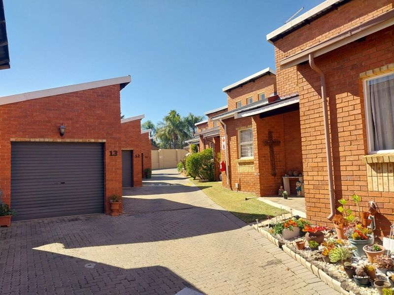 A view of the brick-faced residential units in a retirement village, featuring paved driveways, roller garage doors, and well-maintained exterior infrastructure.