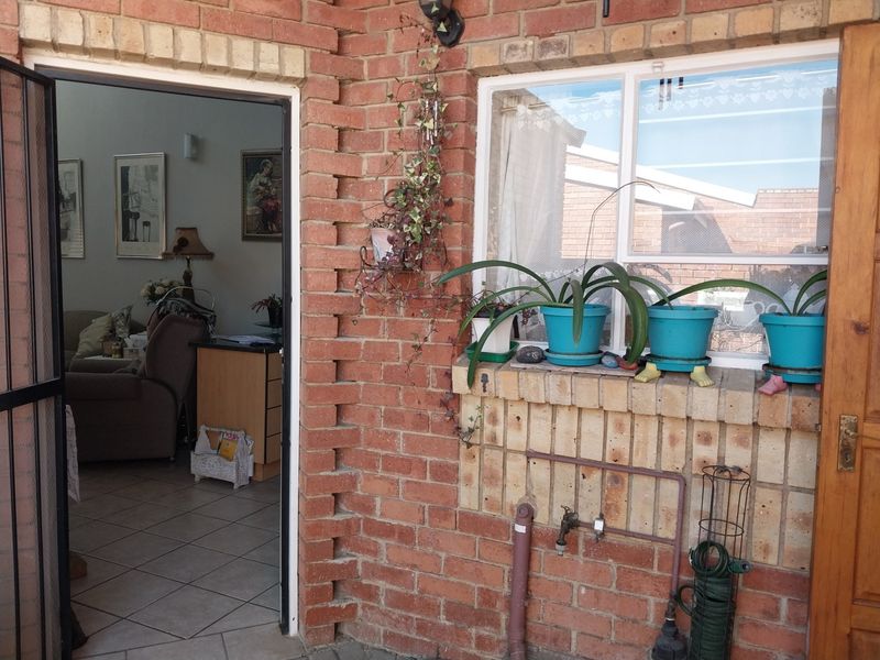 A brick-walled patio area featuring an external water tap, security gate, and a view into the interior living space.