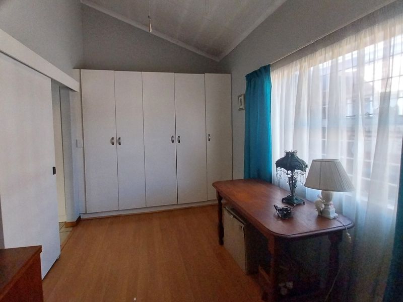 A bedroom featuring laminate flooring, vaulted ceilings, and ample built-in cupboard storage space.
