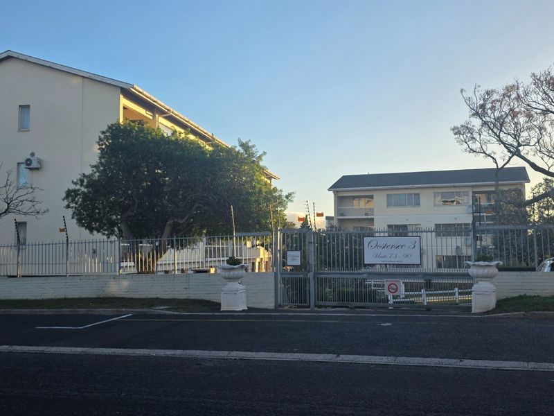 Street view of the apartment complex entrance featuring secure gated access and multi-story residential buildings.