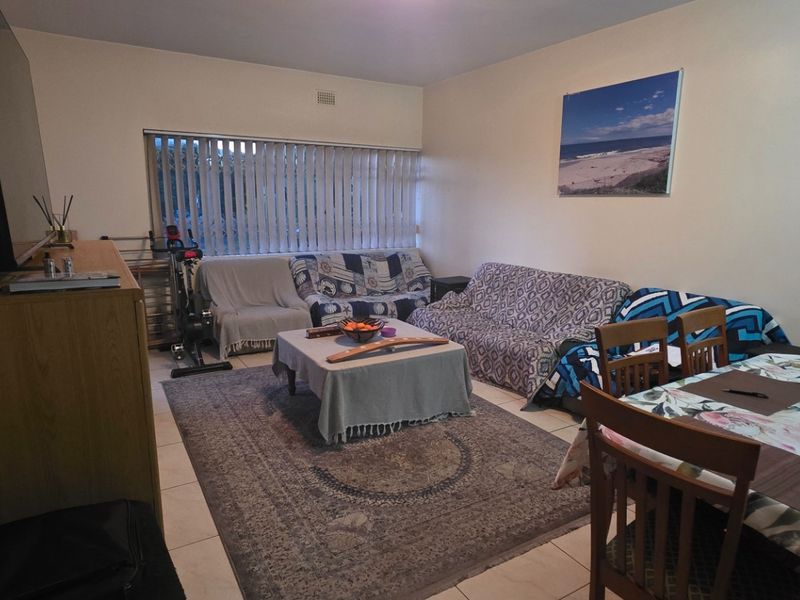 Open plan living and dining area featuring tiled flooring and large windows with vertical blinds, offering a functional layout for daily living.
