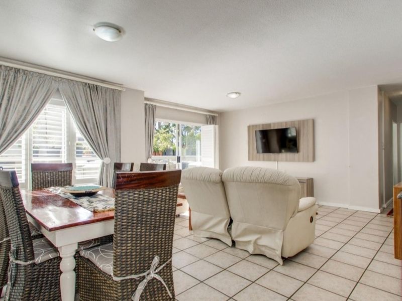 Open-plan living and dining area featuring tiled flooring, neutral walls, and sliding glass doors leading to an outdoor space.