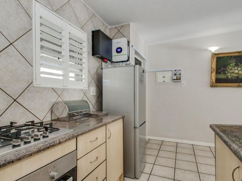 Kitchen featuring granite countertops, built-in oven, gas hob, tiled splashback, and an integrated inverter system for power backup.