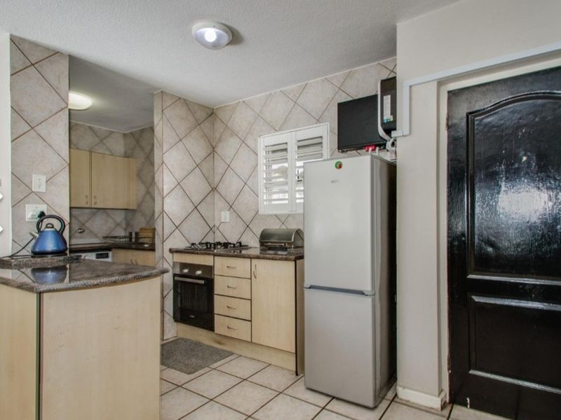 Functional kitchen featuring built-in cabinetry, granite countertops, gas hob, and tiled splashbacks, offering a practical layout for daily cooking needs.