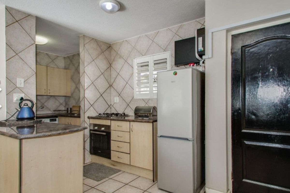 Functional kitchen featuring built-in cabinetry, granite countertops, gas hob, and tiled splashbacks, offering a practical layout for daily cooking needs.