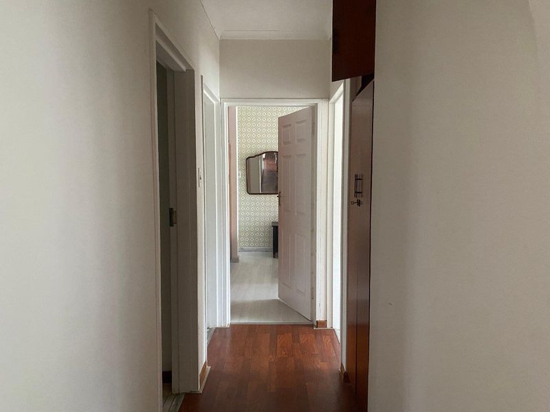 A functional hallway featuring laminate flooring and built-in storage cupboards, providing access to adjacent rooms within the home.