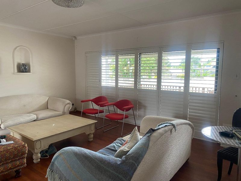 Spacious living room featuring hardwood flooring, a decorative wall niche, and large plantation shutters allowing for natural light.