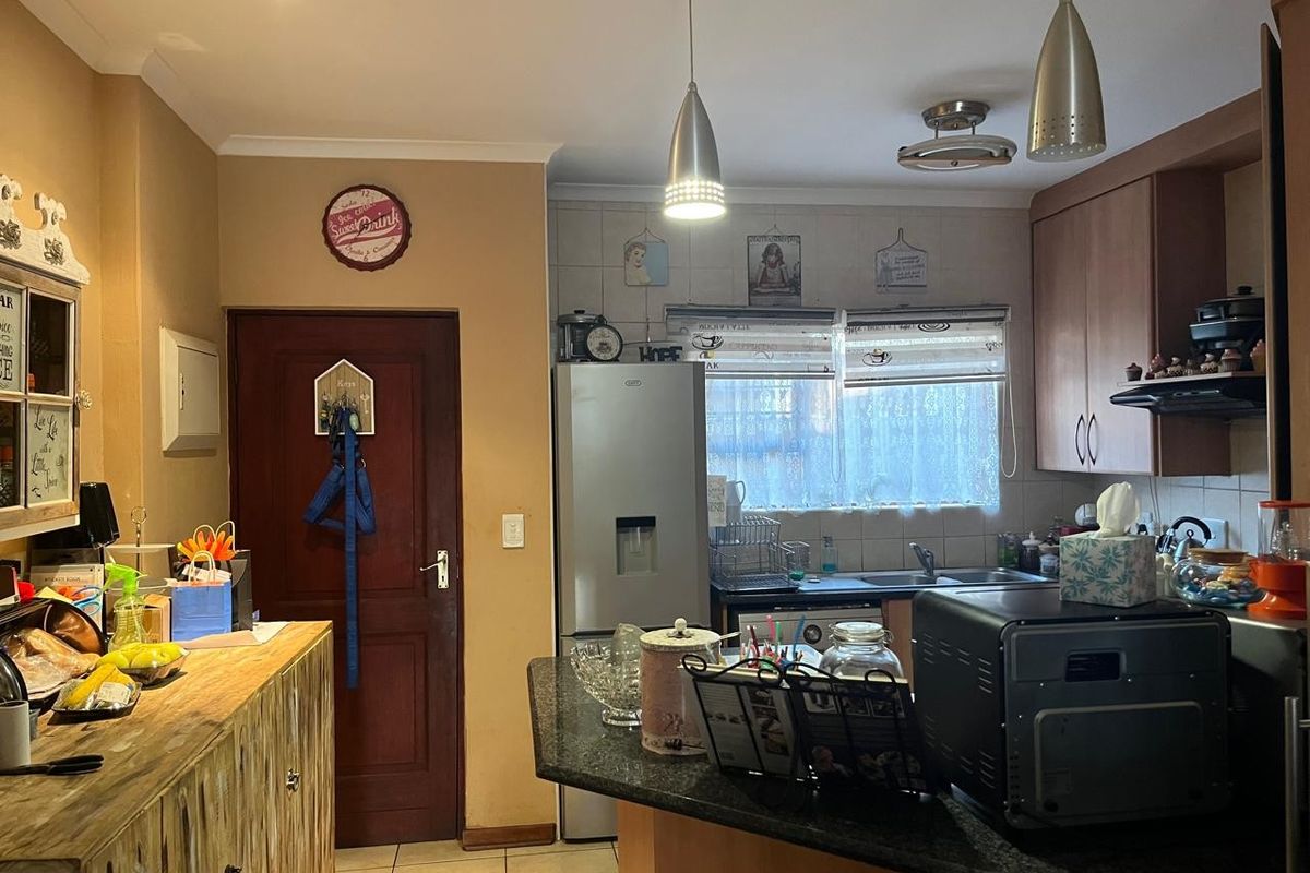 A functional kitchen featuring built-in cabinetry, granite countertops, a stainless steel sink, and tiled flooring, illuminated by pendant and recessed lighting.