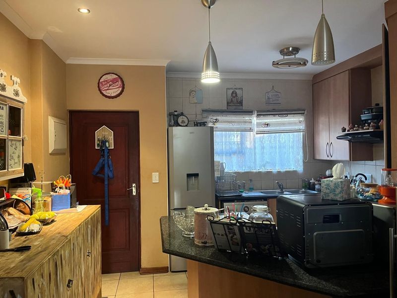 A functional kitchen featuring built-in cabinetry, granite countertops, a stainless steel sink, and tiled flooring, illuminated by pendant and recessed lighting.