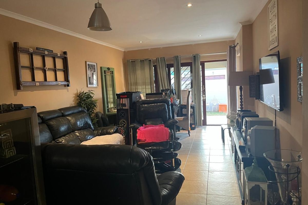 A living room featuring tiled flooring, recessed lighting, and a sliding glass door providing access to the outdoor area.