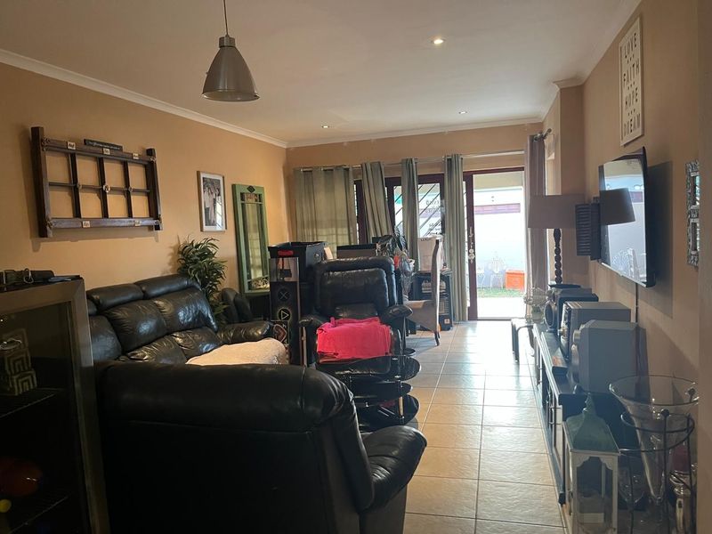 A living room featuring tiled flooring, recessed lighting, and a sliding glass door providing access to the outdoor area.