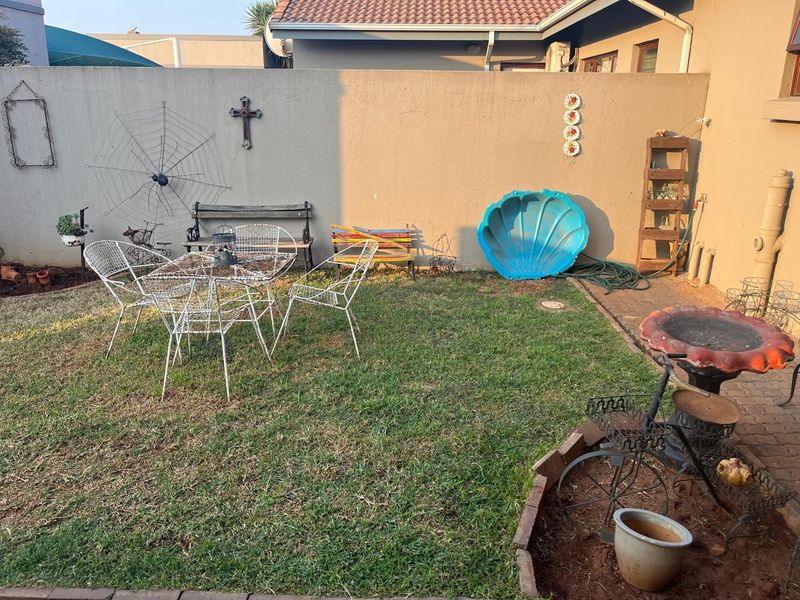 A private rear garden area featuring a lawn, brick-edged garden bed, and a high boundary wall, offering potential for outdoor landscaping and improvement.