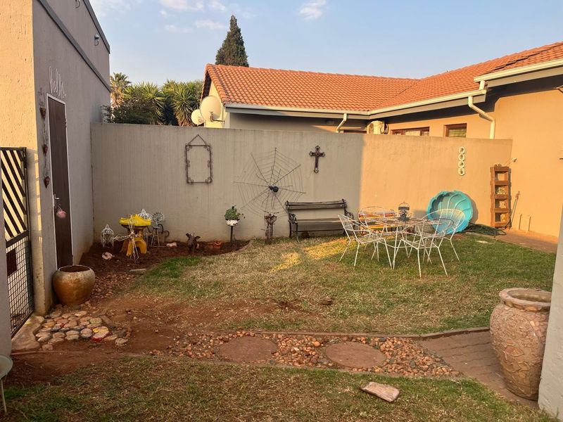 A private rear garden area featuring a lawn, paved pathway, and high boundary walls, offering a blank canvas for outdoor landscaping and improvement.
