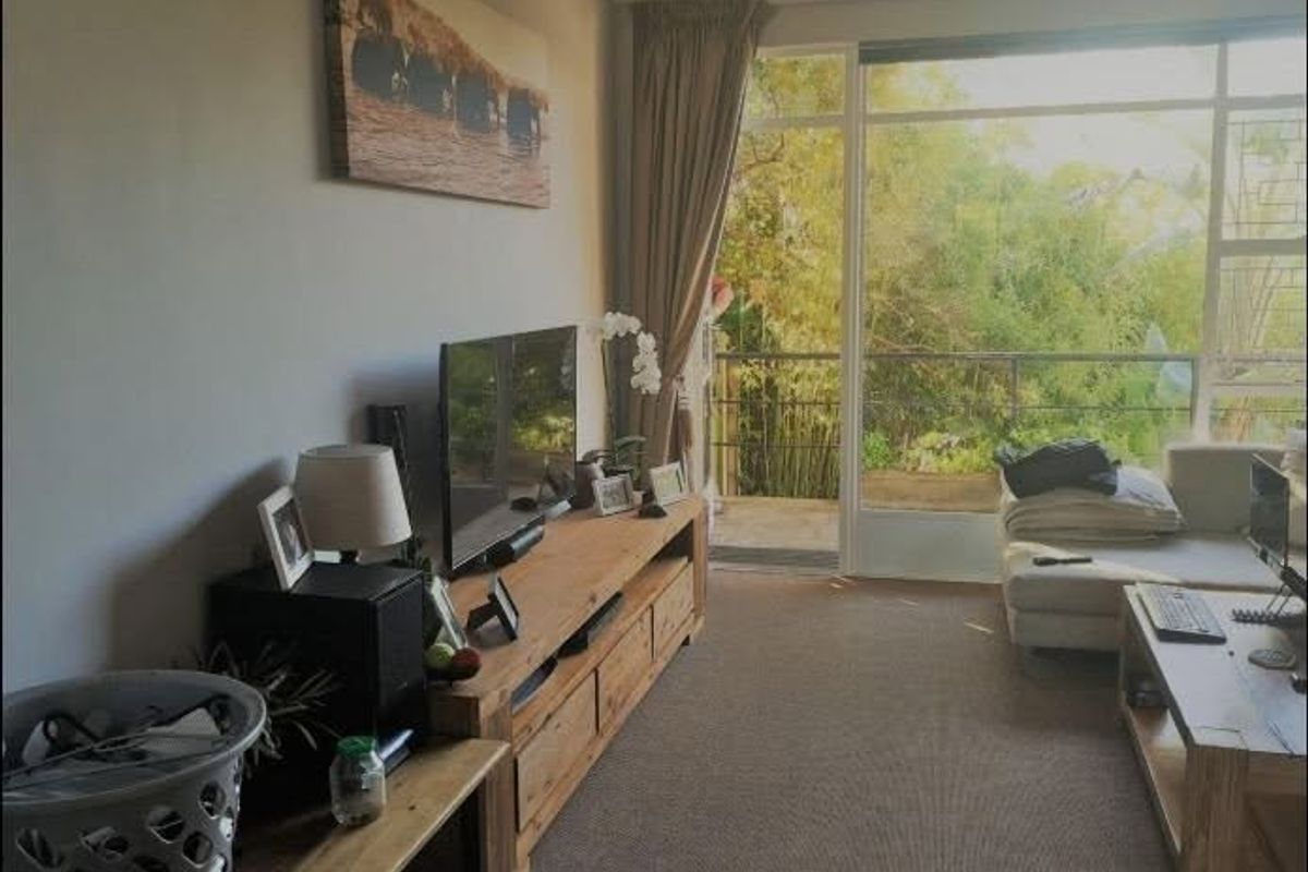 A living room featuring carpeted flooring and a large sliding glass door that provides access to an outdoor balcony area.