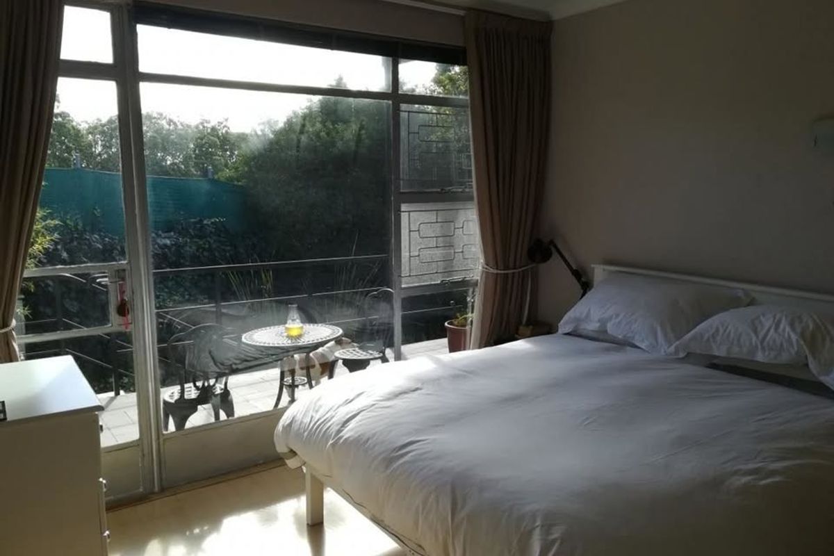 A bedroom featuring laminate flooring and a large sliding glass door providing access to an outdoor patio area.