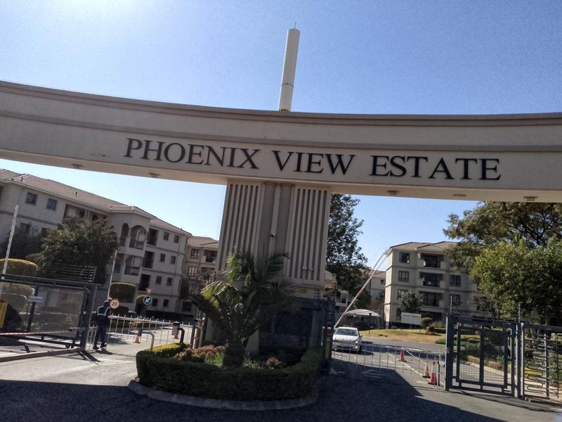 The main entrance gate and security access point for Phoenix View Estate, featuring a controlled boom gate and perimeter security fencing.