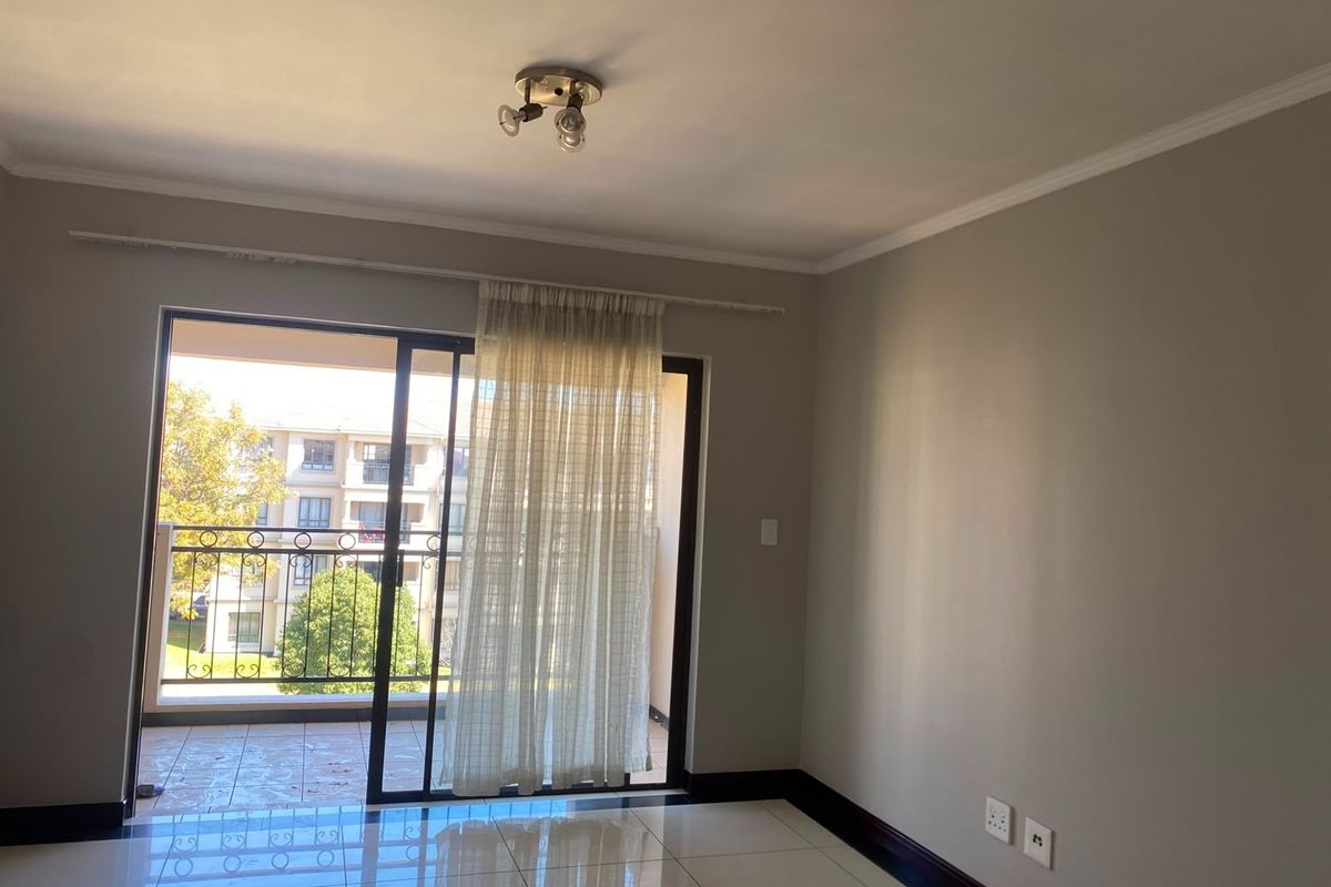 A bright, empty living room featuring tiled floors, neutral walls, and a sliding glass door that opens onto a private balcony.