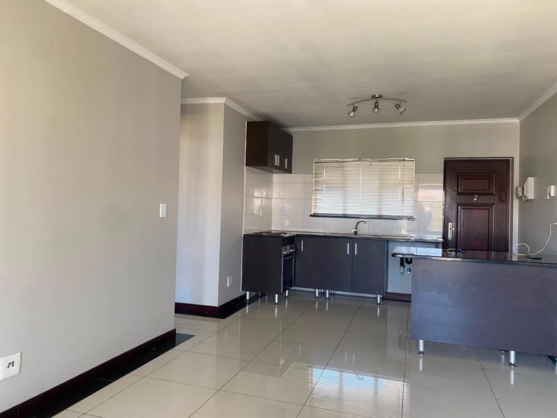 Open plan kitchen and living area featuring dark cabinetry, a kitchen island, tiled flooring, and neutral wall finishes.