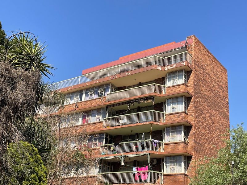 Exterior view of a multi-story brick apartment building featuring multiple balconies with metal railings and standard window configurations.