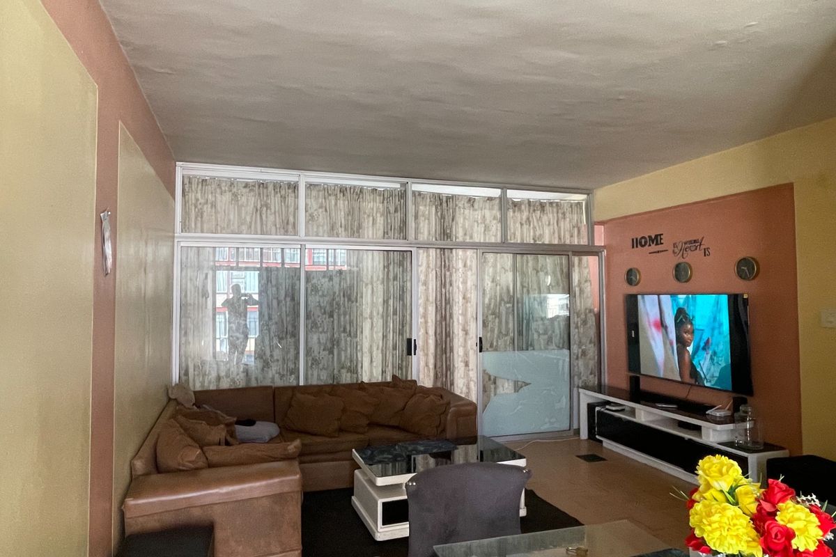 Living room featuring laminate flooring and large sliding glass doors with aluminium frames, providing access to an outdoor area.