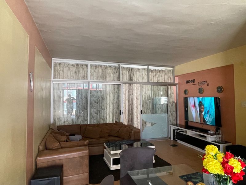 Living room featuring laminate flooring and large sliding glass doors with aluminium frames, providing access to an outdoor area.