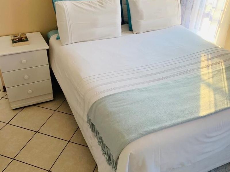 A bedroom featuring neutral wall paint and ceramic floor tiles, providing a functional and well-lit sleeping space.
