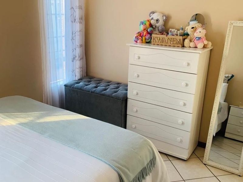 A bedroom featuring tiled flooring and a window with a curtain rod, providing a functional and well-lit living space.