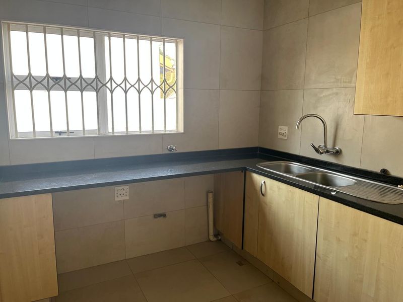 A functional kitchen area featuring laminate cabinetry, granite countertops, a double bowl sink, and tiled splashbacks, ready for appliance installation.