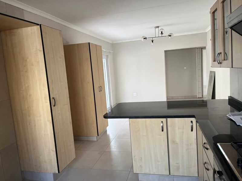 A clean, modern kitchen featuring light wood cabinetry, dark granite countertops, and tiled flooring, offering a functional and bright workspace.