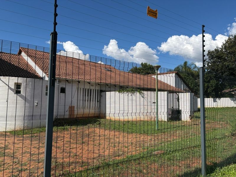 Rear exterior view of the property featuring a tiled roof, security fencing, and a paved yard area.