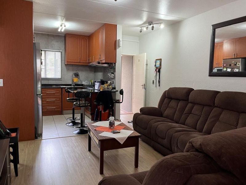Open plan living area featuring a kitchen with wood-finish cabinetry, granite countertops, and laminate flooring, seamlessly connected to the lounge space.