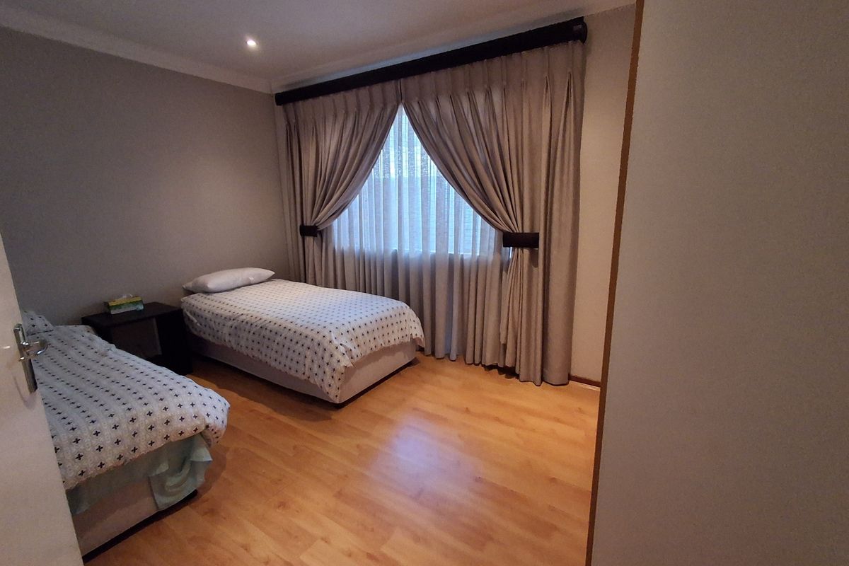 A well-maintained bedroom featuring laminate flooring, recessed downlighting, and neutral wall finishes, providing a comfortable and functional living space.