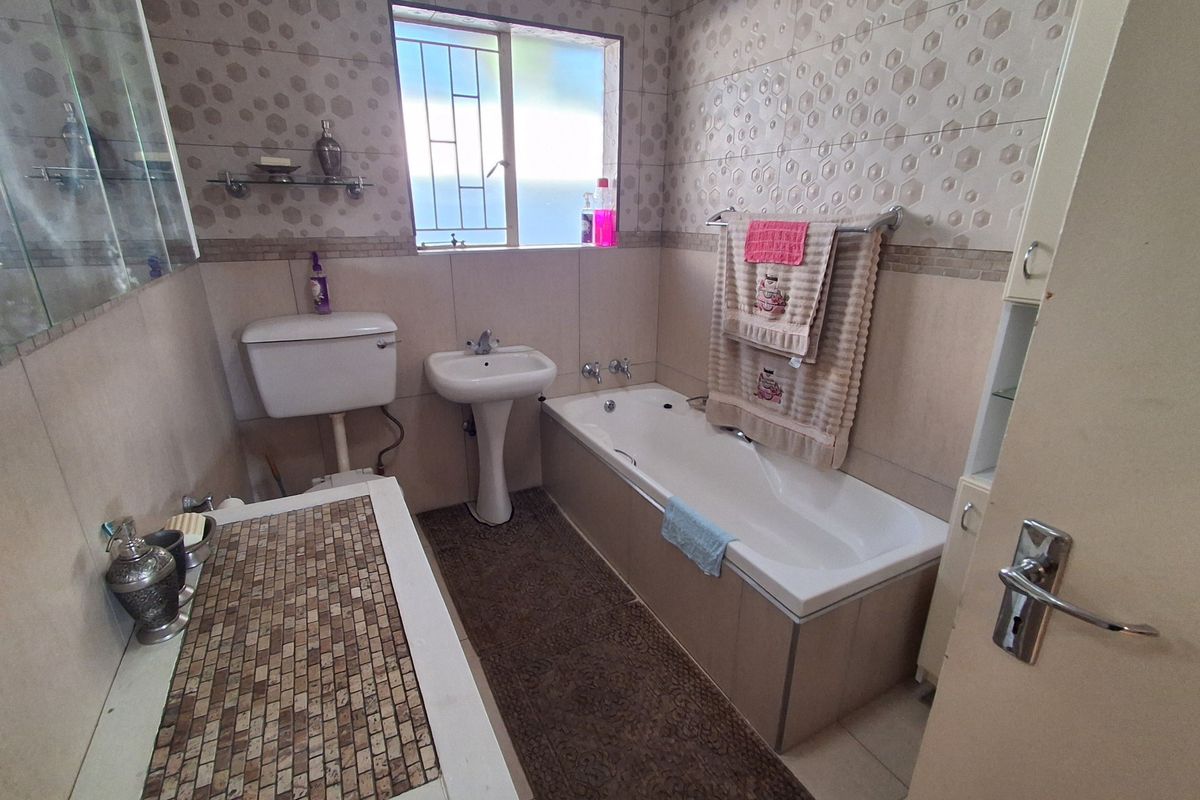 A functional bathroom featuring a pedestal basin, bathtub, and toilet, finished with patterned wall tiling and floor tiles.