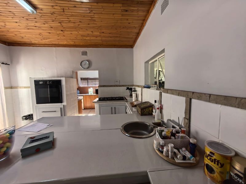 A functional kitchen featuring a built-in oven, gas hob, tiled backsplash, and a distinctive timber-clad ceiling, offering a practical layout with ample counter space.