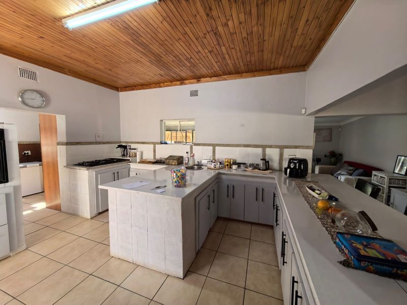 Spacious kitchen featuring a large tiled island, gas hob, ample cabinetry, and a distinctive timber ceiling, offering a functional layout with potential for modernization.