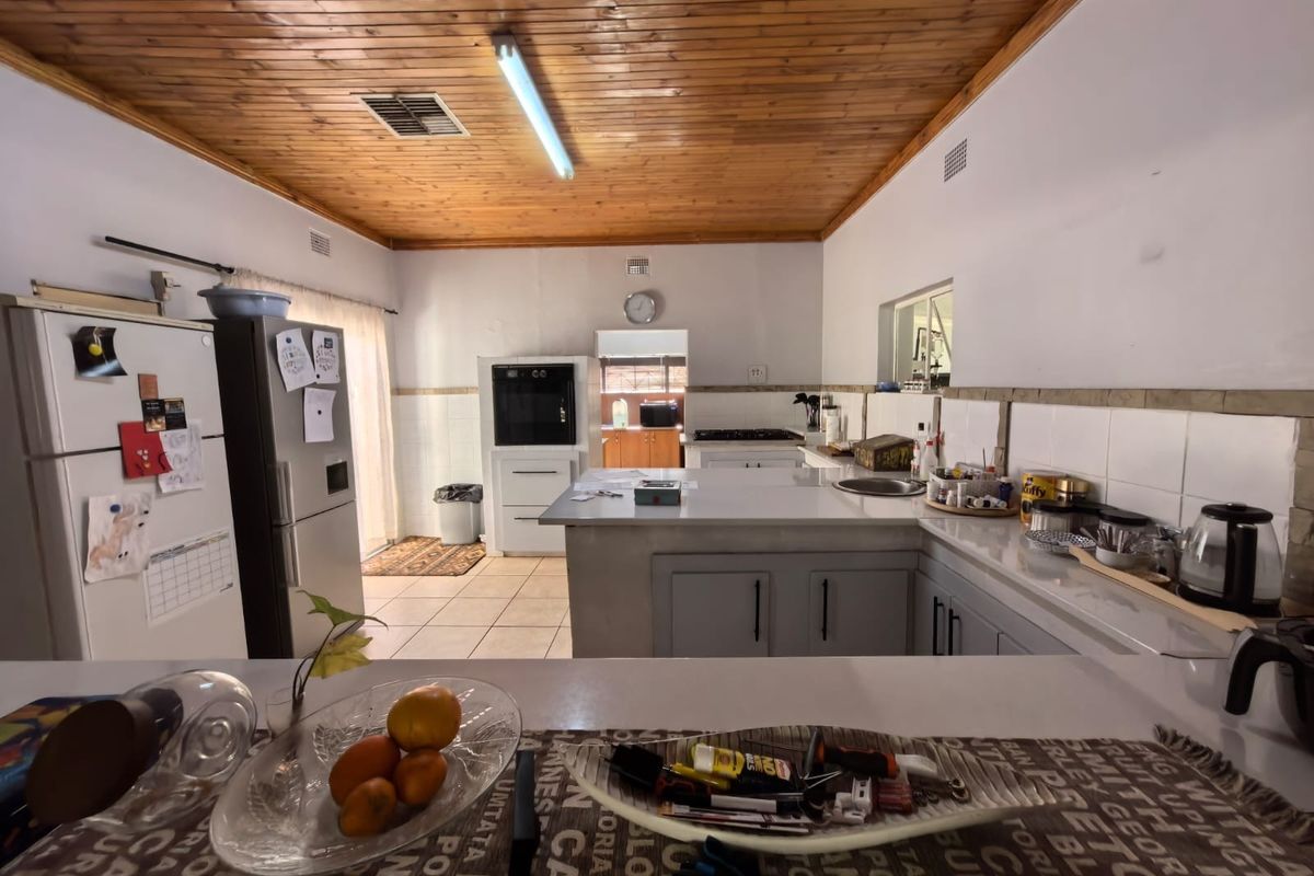 Spacious kitchen featuring a timber ceiling, tiled countertops, built-in oven, and gas hob, offering a functional layout with ample workspace.