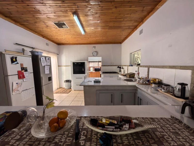 Spacious kitchen featuring a timber ceiling, tiled countertops, built-in oven, and gas hob, offering a functional layout with ample workspace.